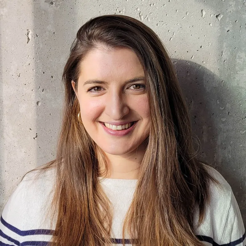 Tania Amardeil, smiling, in front of a concrete wall